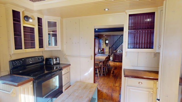 kitchen with electric range, dark hardwood / wood-style flooring, white cabinets, and crown molding