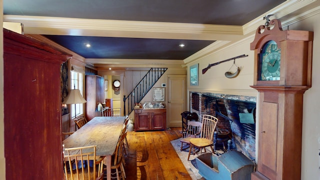 dining room featuring hardwood / wood-style flooring, a premium fireplace, and crown molding