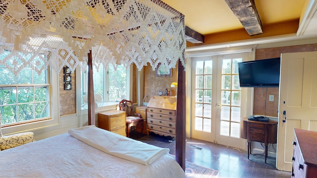 bedroom with beamed ceiling, french doors, and multiple windows