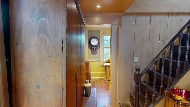 hall featuring wooden walls, hardwood / wood-style floors, and ornamental molding