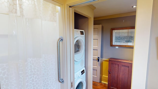 washroom featuring ornamental molding and stacked washer / dryer