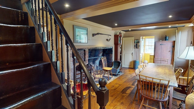 dining room with a fireplace, wood-type flooring, and ornamental molding