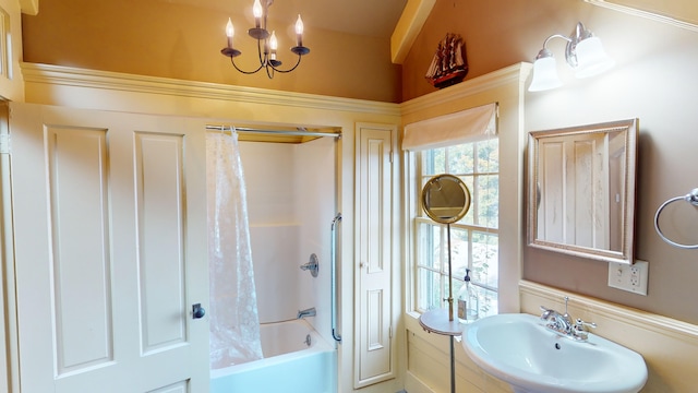 bathroom with shower / tub combo, a notable chandelier, and sink