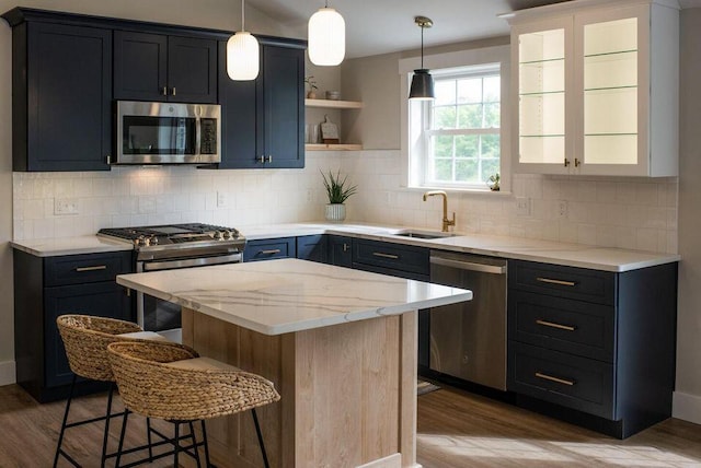 kitchen with sink, appliances with stainless steel finishes, light hardwood / wood-style floors, and a center island