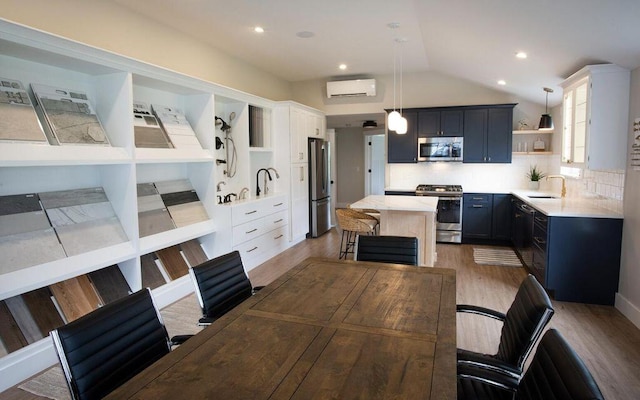 kitchen featuring pendant lighting, a kitchen island, blue cabinets, appliances with stainless steel finishes, and sink