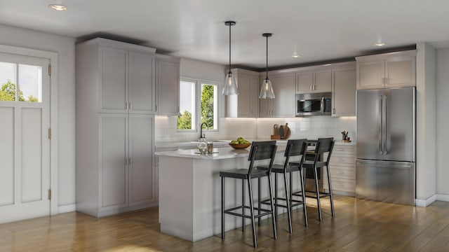 kitchen featuring a kitchen breakfast bar, appliances with stainless steel finishes, hanging light fixtures, gray cabinetry, and a kitchen island