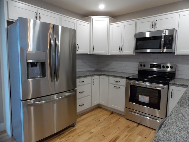 kitchen featuring backsplash, light hardwood / wood-style floors, stainless steel appliances, and white cabinets