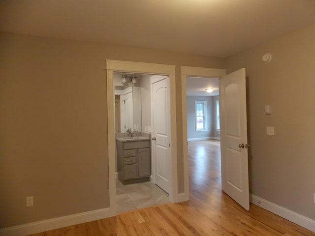 unfurnished bedroom featuring a closet, sink, and light tile floors