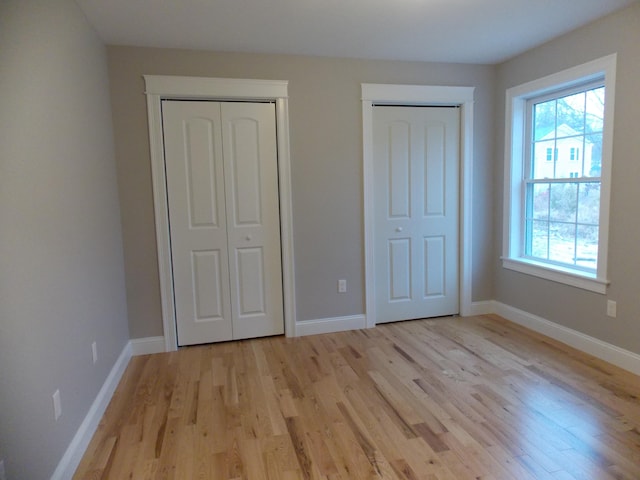 unfurnished bedroom featuring two closets and light hardwood / wood-style flooring