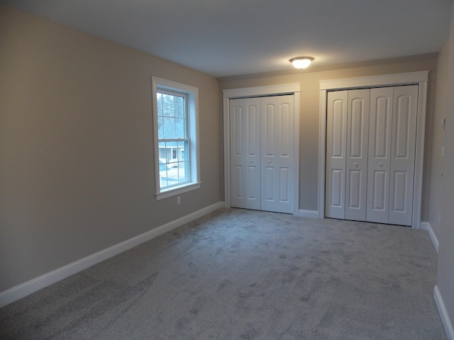 unfurnished bedroom with multiple closets and carpet flooring