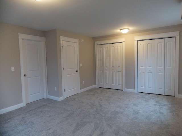 unfurnished bedroom with light carpet and multiple closets