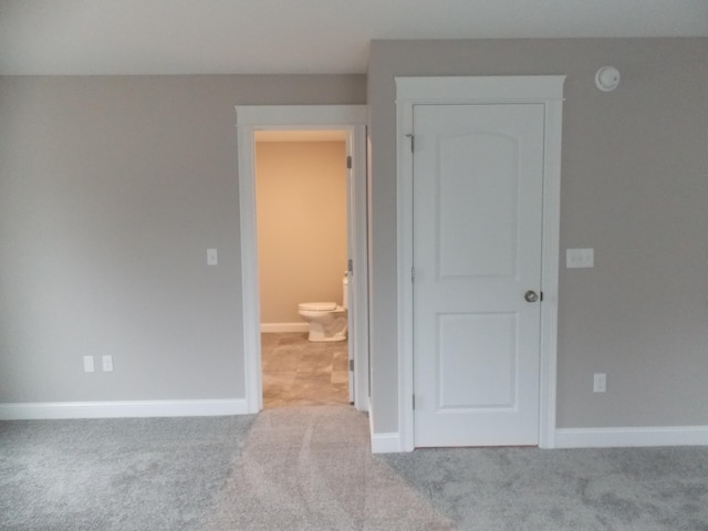 unfurnished bedroom with ensuite bath and light colored carpet