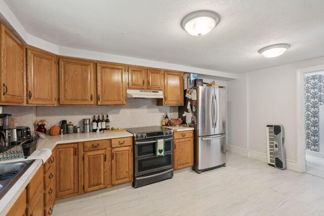 kitchen with appliances with stainless steel finishes, light tile patterned flooring, and a textured ceiling