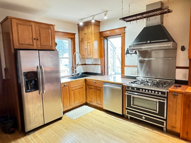 kitchen featuring appliances with stainless steel finishes, sink, light wood-type flooring, and rail lighting