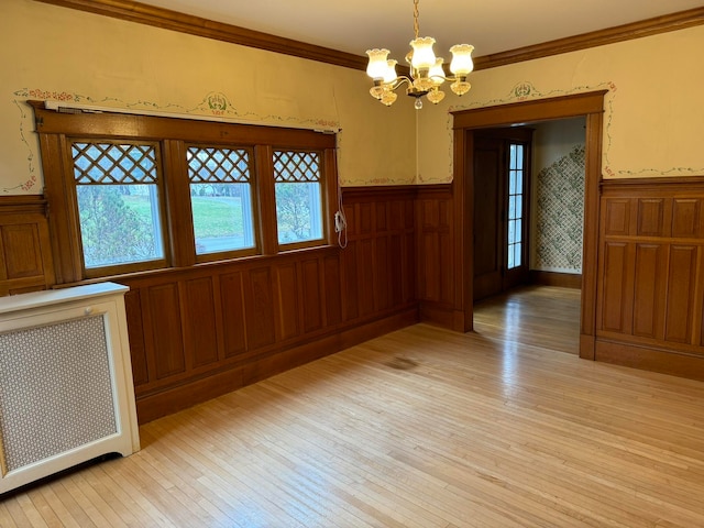 unfurnished room with ornamental molding, light hardwood / wood-style floors, and a notable chandelier