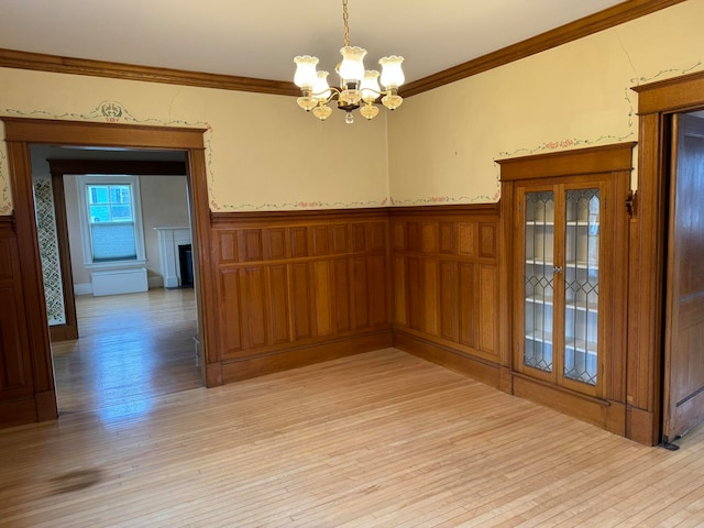 unfurnished room with crown molding, light hardwood / wood-style floors, and a chandelier