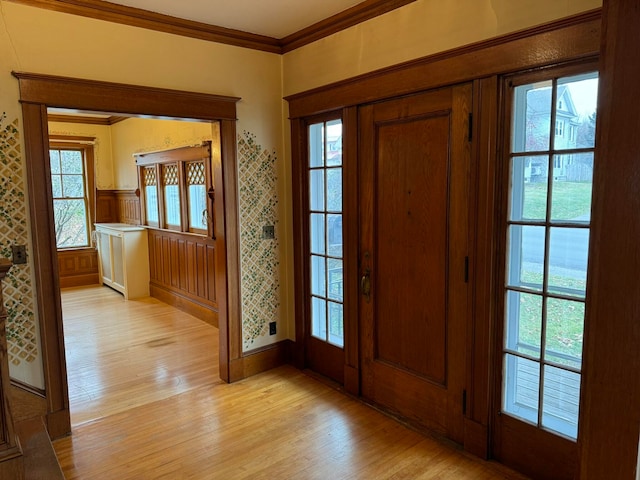 entryway with crown molding and light wood-type flooring