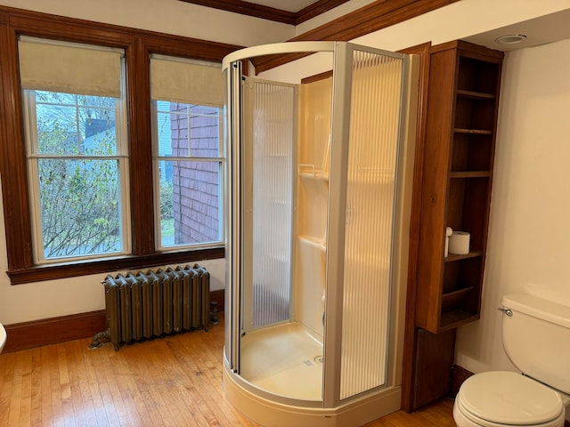 bathroom featuring hardwood / wood-style floors, toilet, radiator, and ornamental molding