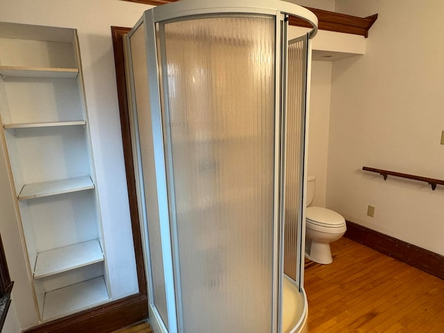 bathroom featuring hardwood / wood-style floors, toilet, and a shower with door