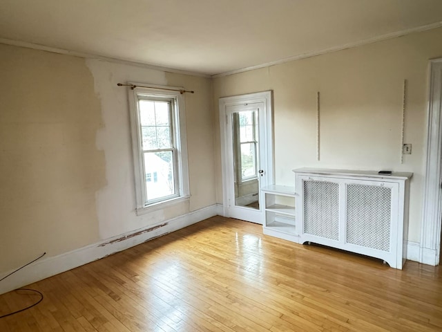 spare room with radiator heating unit and light hardwood / wood-style floors