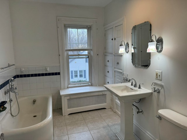 bathroom featuring a tub, tile flooring, radiator heating unit, and toilet