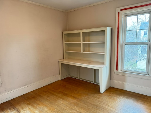 unfurnished office featuring crown molding, light wood-type flooring, and a wealth of natural light