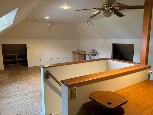 interior space with vaulted ceiling with skylight, wood-type flooring, and ceiling fan