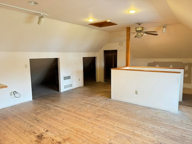 additional living space with ceiling fan, lofted ceiling, and light wood-type flooring