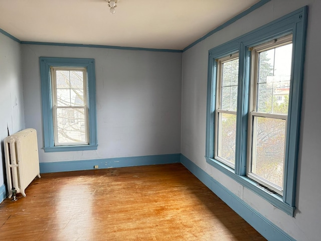 unfurnished room with a healthy amount of sunlight, radiator, and light wood-type flooring