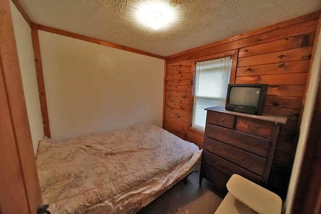 carpeted bedroom featuring wood walls and a textured ceiling