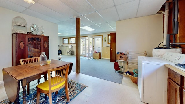 dining space featuring washer / clothes dryer, wooden walls, and a paneled ceiling