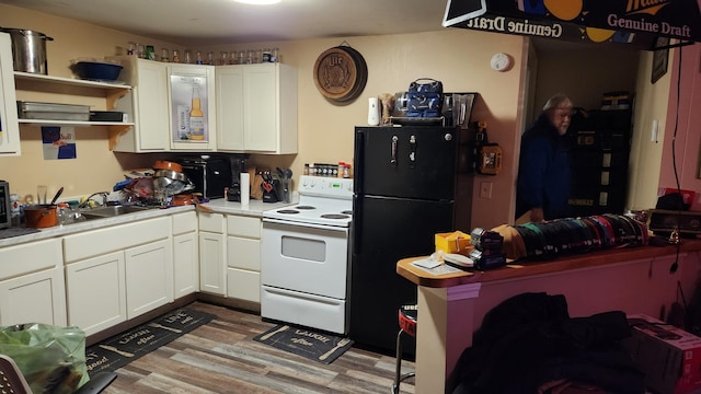 kitchen with black refrigerator, white cabinets, white range with electric stovetop, and light hardwood / wood-style floors