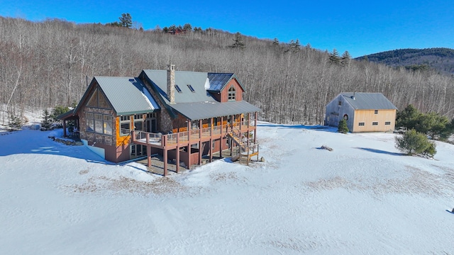 snow covered back of property with a wooden deck