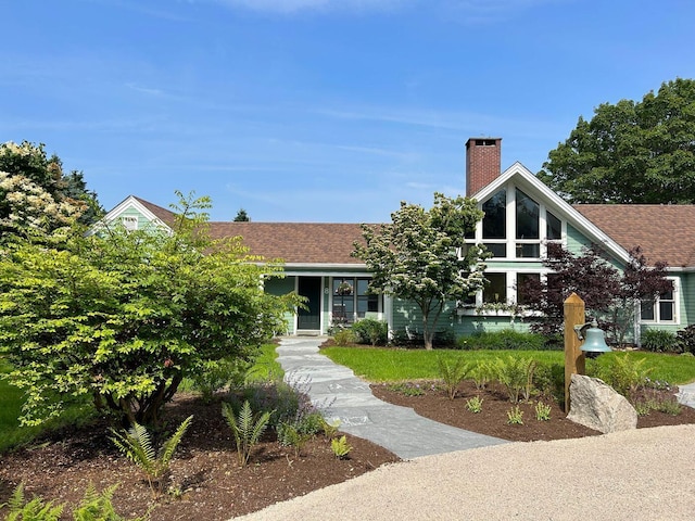 view of front of home featuring a chimney and a shingled roof