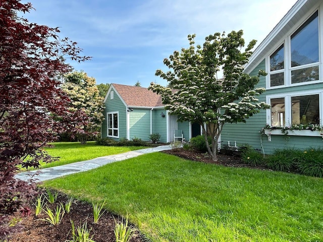 view of front of house with a front lawn and roof with shingles