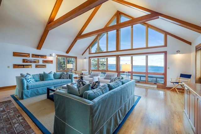 living room with high vaulted ceiling, a water view, light wood-type flooring, and beam ceiling