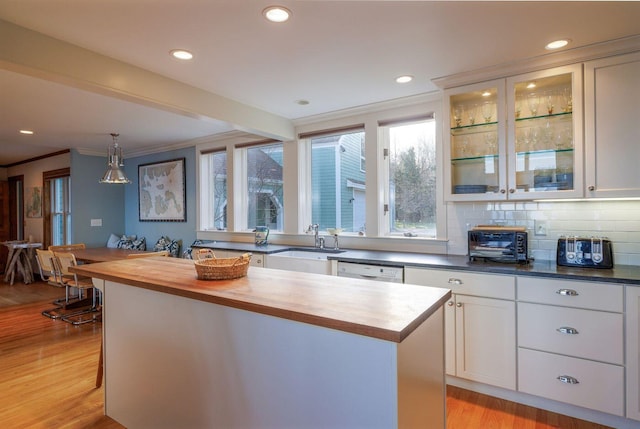 kitchen featuring white cabinets, backsplash, sink, butcher block countertops, and light hardwood / wood-style flooring