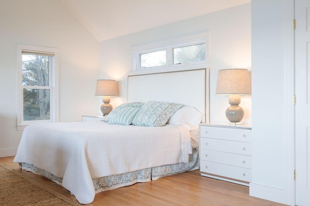 bedroom featuring light hardwood / wood-style flooring, vaulted ceiling, and multiple windows