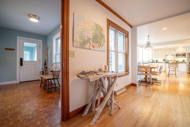 entrance foyer with a baseboard radiator, light parquet flooring, and crown molding