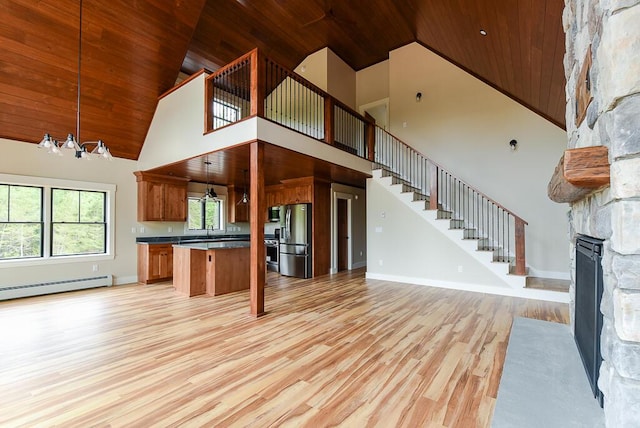 kitchen with appliances with stainless steel finishes, a towering ceiling, decorative light fixtures, and wooden ceiling