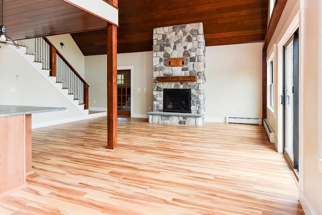 unfurnished living room featuring a fireplace, wooden ceiling, baseboard heating, and vaulted ceiling