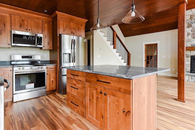 kitchen featuring appliances with stainless steel finishes, light wood-type flooring, decorative light fixtures, wooden ceiling, and a fireplace