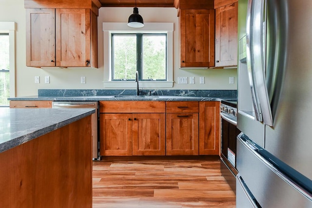 kitchen with pendant lighting, sink, appliances with stainless steel finishes, and dark stone counters