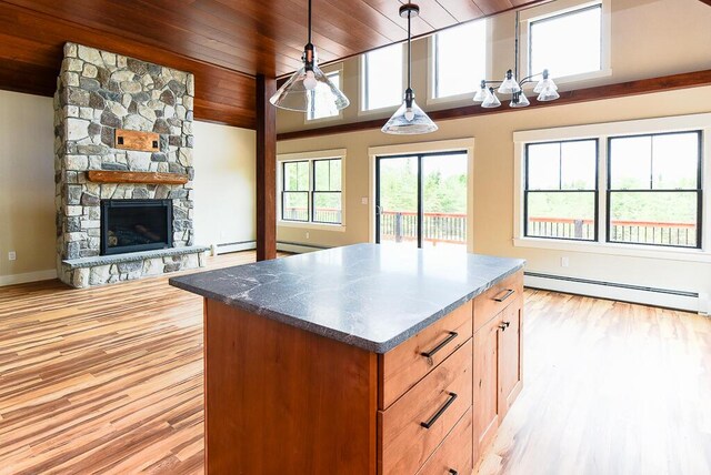 kitchen with wooden ceiling, hanging light fixtures, baseboard heating, a stone fireplace, and light hardwood / wood-style floors