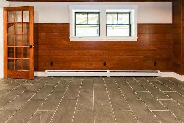 unfurnished room featuring wooden walls and a baseboard heating unit