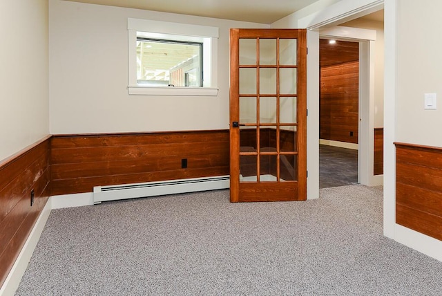 spare room featuring wood walls, french doors, carpet floors, and a baseboard heating unit