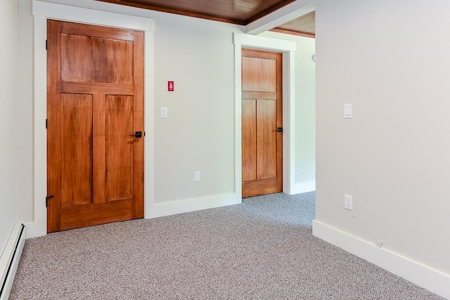 carpeted spare room featuring wooden ceiling and a baseboard heating unit