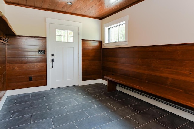 foyer entrance with wood walls, ornamental molding, wood ceiling, and a baseboard heating unit