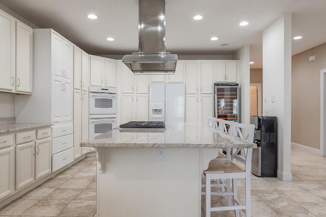 kitchen with white appliances, light stone countertops, a kitchen island, and island exhaust hood