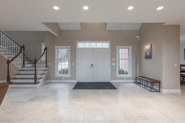 entryway with a high ceiling, a healthy amount of sunlight, and light tile patterned floors